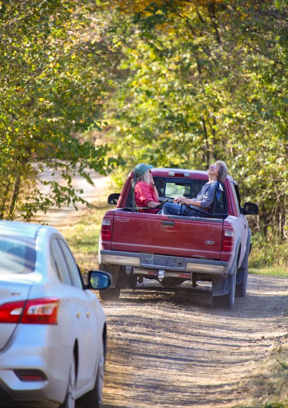 Two women ride in the back of a truck to enjoy the fall foliage during the Poosey Conservation Area fall tour