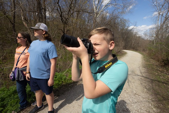 young person taking nature pictures on trail with two others