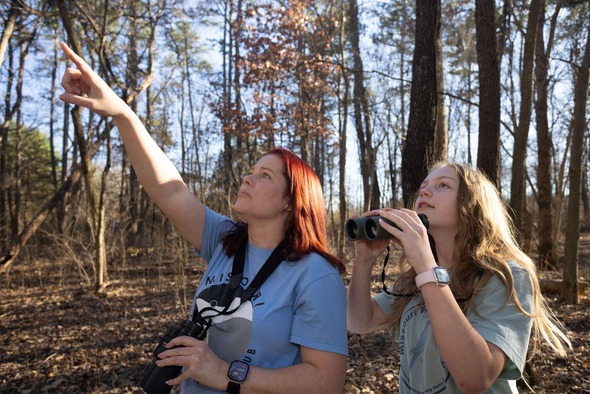 two women birdwatching in woods