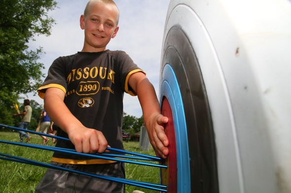 boy pulling arrow from archery target