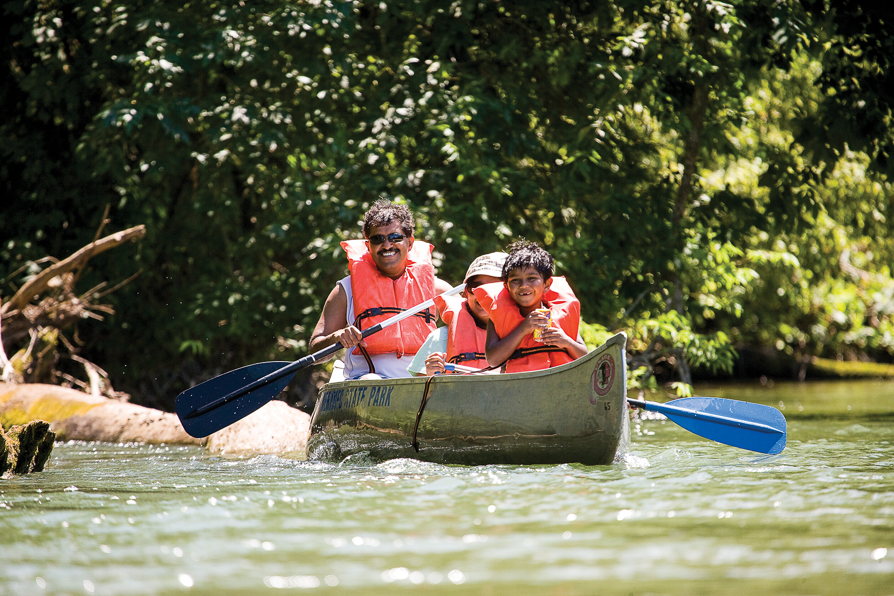 A family canoes down a river.